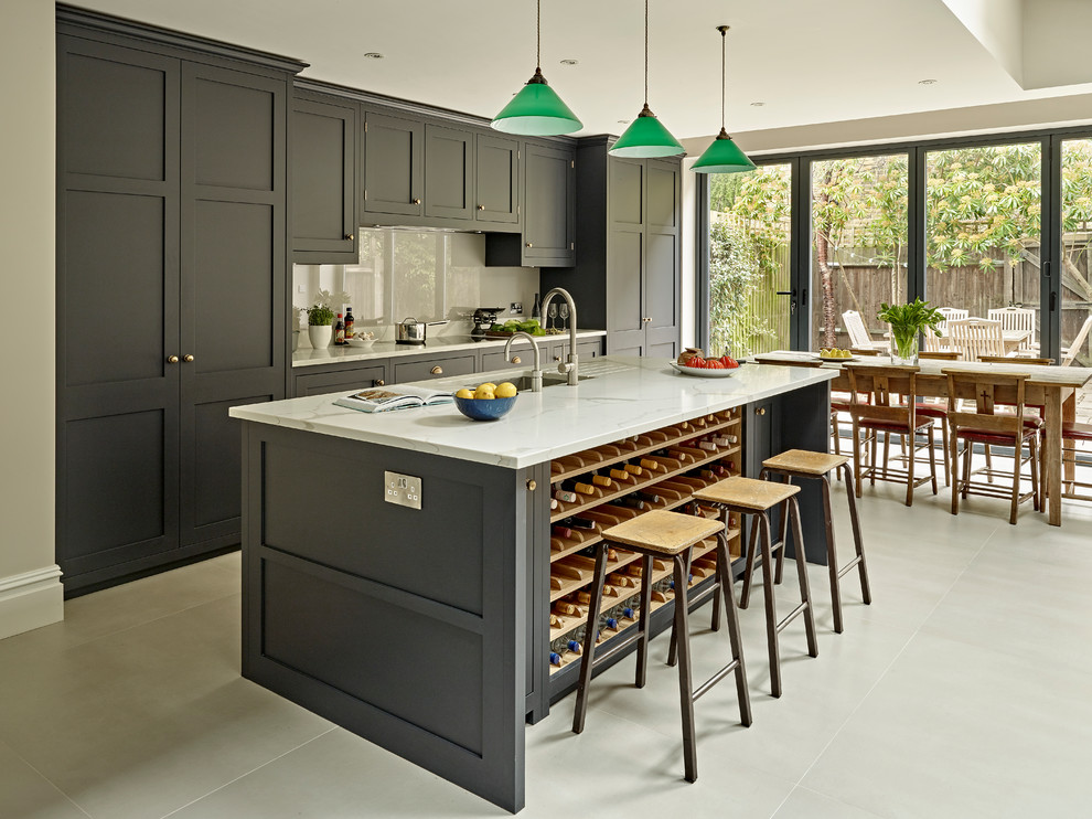 Large transitional eat-in kitchen in London with shaker cabinets, black cabinets, solid surface benchtops, grey splashback, porcelain floors, with island and grey floor.
