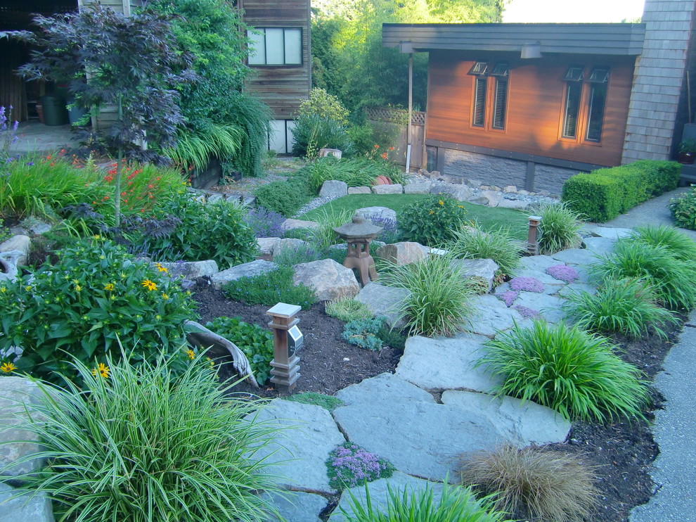 This is an example of a mid-sized midcentury front yard full sun formal garden for summer in Vancouver with a garden path and natural stone pavers.