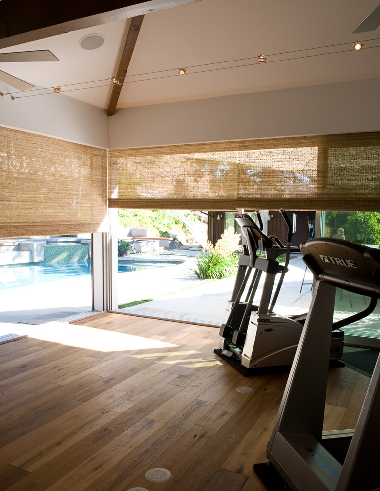 Photo of a mid-sized transitional home weight room in Los Angeles with white walls and medium hardwood floors.