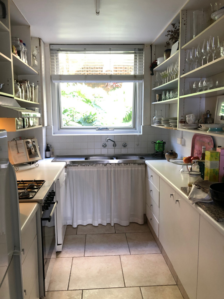 Photo of a small contemporary galley separate kitchen in Sydney with a double-bowl sink, open cabinets, white cabinets, laminate benchtops, white splashback, mosaic tile splashback, white appliances, porcelain floors, no island, pink floor and white benchtop.
