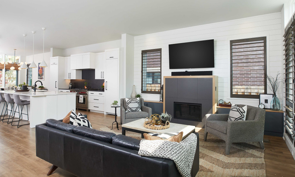 Photo of a mid-sized contemporary open concept family room in Grand Rapids with white walls, a wall-mounted tv, medium hardwood floors and a ribbon fireplace.