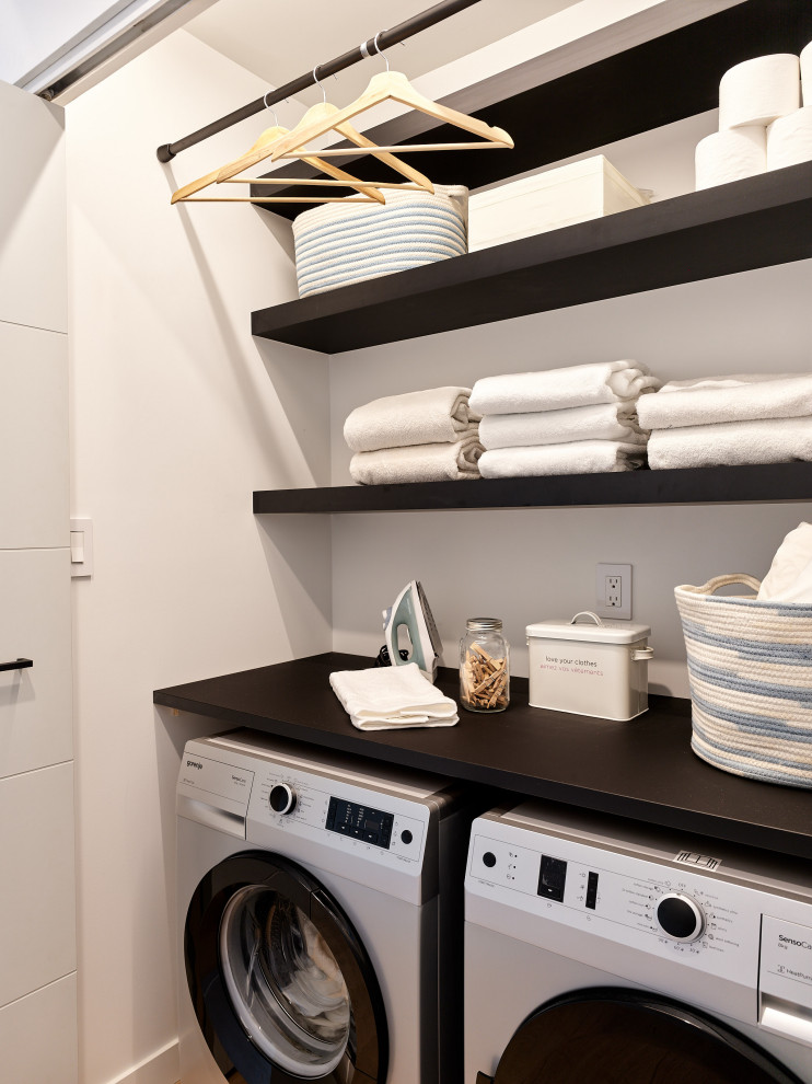Inspiration for a small contemporary single-wall laundry cupboard in Vancouver with open cabinets, black cabinets, wood worktops, white walls, concrete flooring, a side by side washer and dryer, grey floors and black worktops.