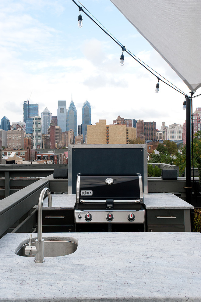 This is an example of a mid-sized contemporary rooftop deck in Philadelphia with an outdoor kitchen and an awning.