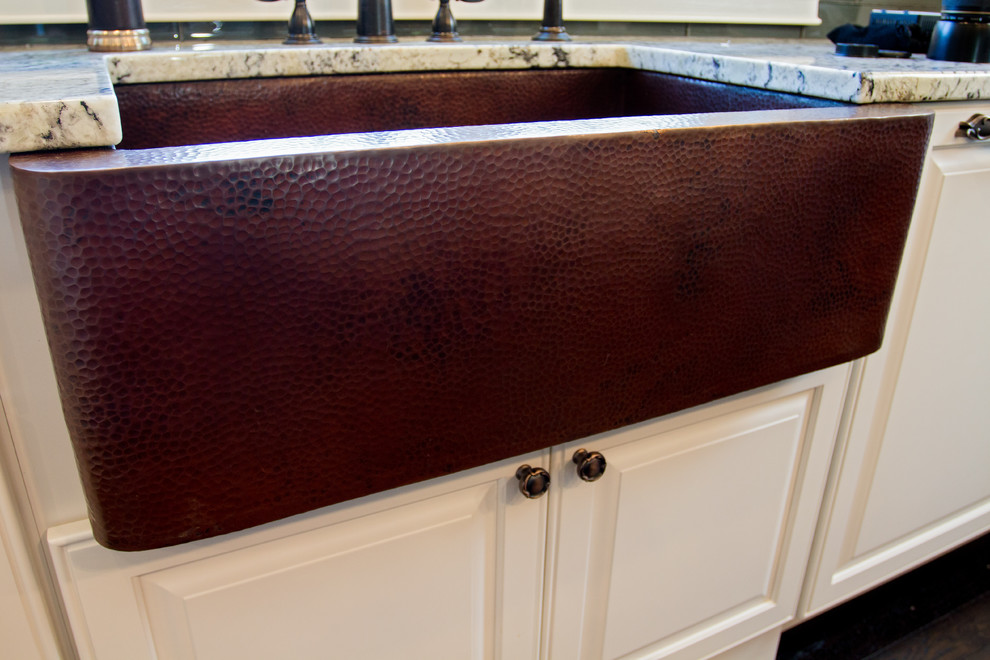 Kitchen - transitional l-shaped dark wood floor kitchen idea in Providence with a farmhouse sink, raised-panel cabinets, granite countertops, gray backsplash, glass tile backsplash, paneled appliances and an island