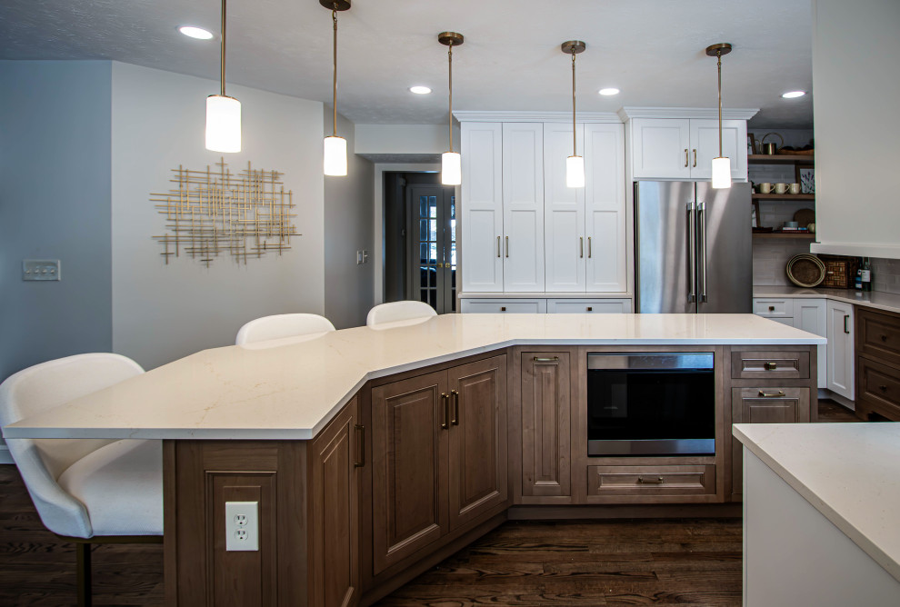 Kitchen - large transitional u-shaped medium tone wood floor and brown floor kitchen idea in Cleveland with an undermount sink, raised-panel cabinets, white cabinets, quartz countertops, white backsplash, ceramic backsplash, stainless steel appliances and beige countertops