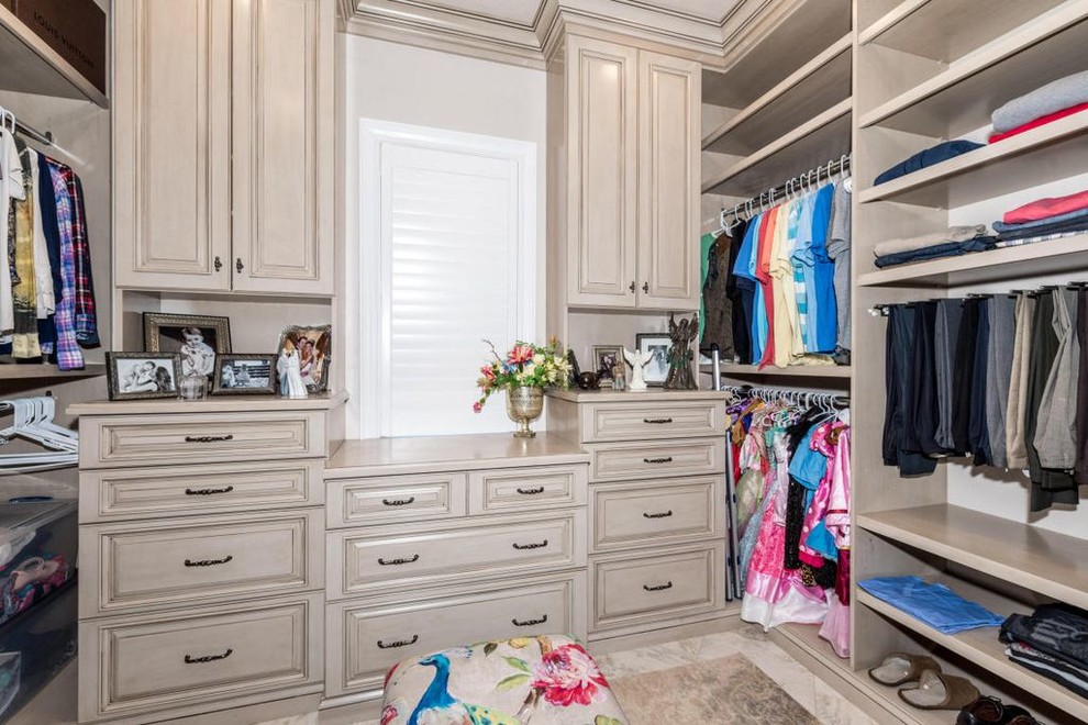 Large mediterranean gender-neutral dressing room in Other with raised-panel cabinets and beige cabinets.