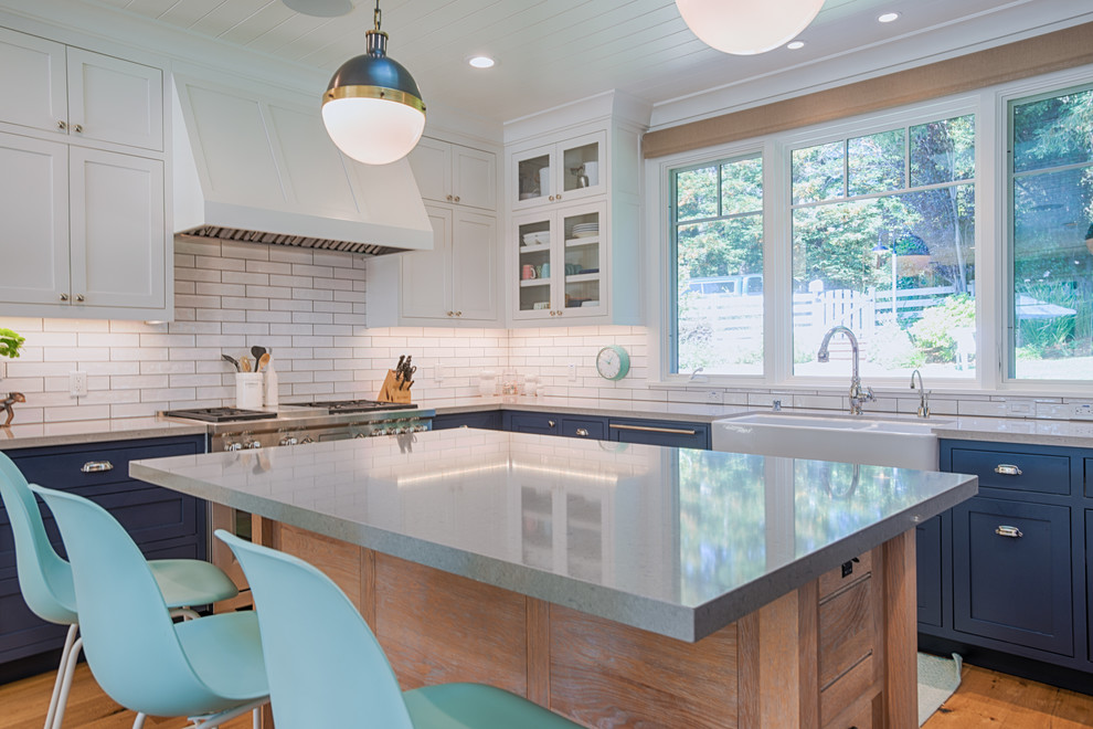 Inspiration for a mid-sized traditional u-shaped open plan kitchen in San Francisco with a farmhouse sink, shaker cabinets, blue cabinets, recycled glass benchtops, white splashback, subway tile splashback, panelled appliances, medium hardwood floors and with island.