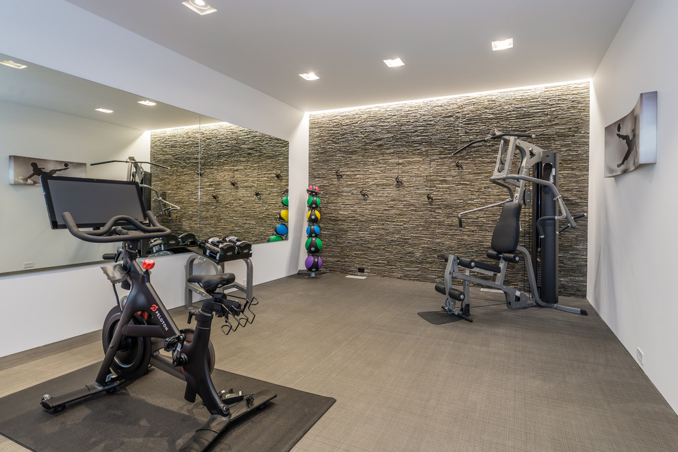 Expansive contemporary home gym in New York with white walls and grey floor.