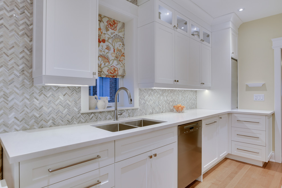 Inspiration for a mid-sized transitional galley kitchen in Toronto with an undermount sink, shaker cabinets, white cabinets, quartz benchtops, grey splashback, stone tile splashback, stainless steel appliances, medium hardwood floors and no island.