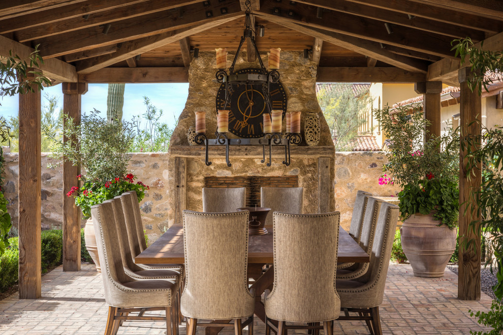 This is an example of an expansive mediterranean backyard patio in Phoenix with a roof extension and brick pavers.