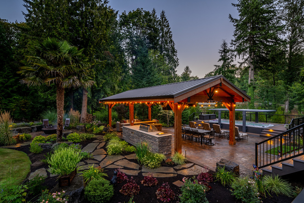 Großer Uriger Garten hinter dem Haus mit Feuerstelle und Natursteinplatten in Seattle