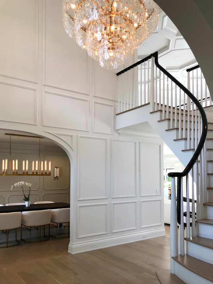 This is an example of a large transitional wood curved staircase in New York with wood risers and wood railing.