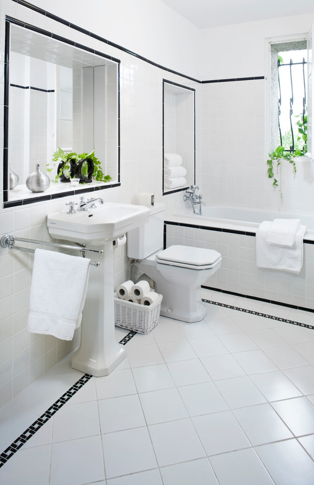 This is an example of a mid-sized traditional master bathroom in Other with a pedestal sink, an alcove tub, a one-piece toilet, black and white tile and white walls.