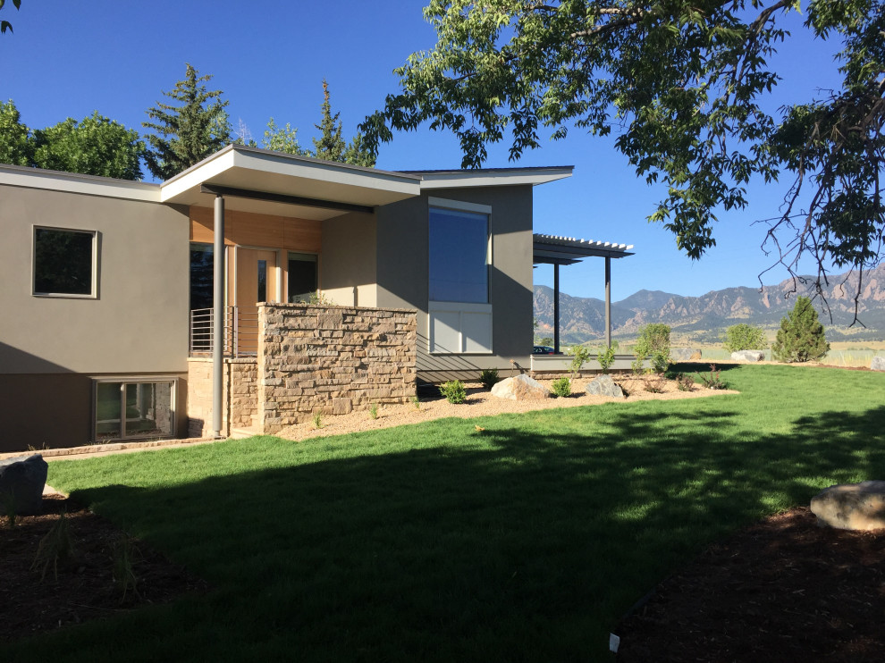 This is an example of a small modern one-storey stucco beige house exterior in Denver with a flat roof and a mixed roof.