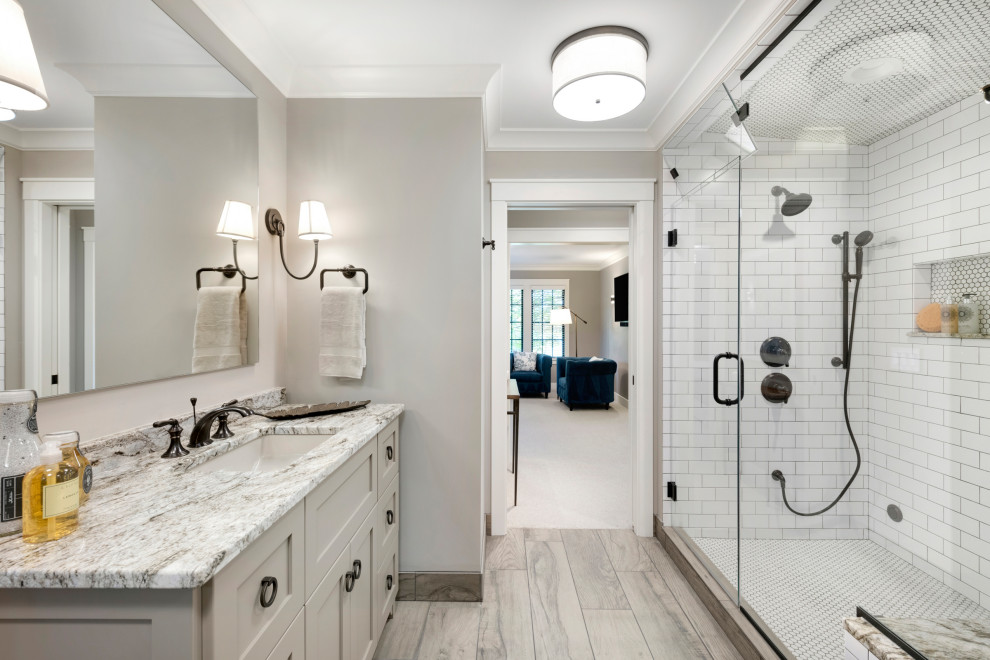 This is an example of a transitional master bathroom in Minneapolis with shaker cabinets, beige cabinets, an alcove shower, subway tile, grey walls, light hardwood floors, an undermount sink, beige floor, a hinged shower door and multi-coloured benchtops.