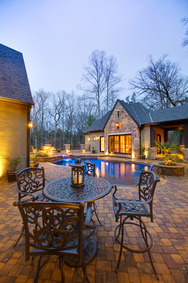 Photo of a traditional custom-shaped pool in Charlotte with brick pavers.