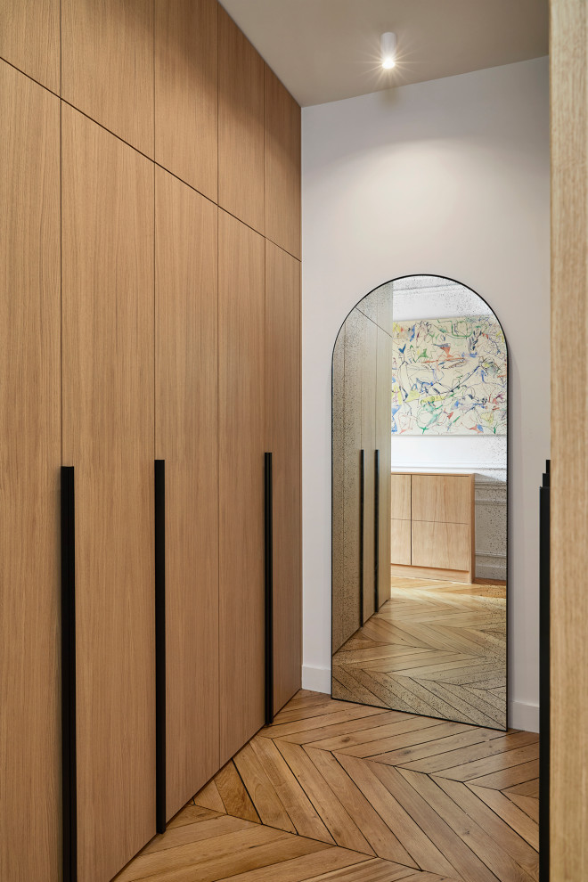This is an example of a medium sized contemporary gender neutral walk-in wardrobe in Paris with flat-panel cabinets, light wood cabinets, light hardwood flooring and brown floors.