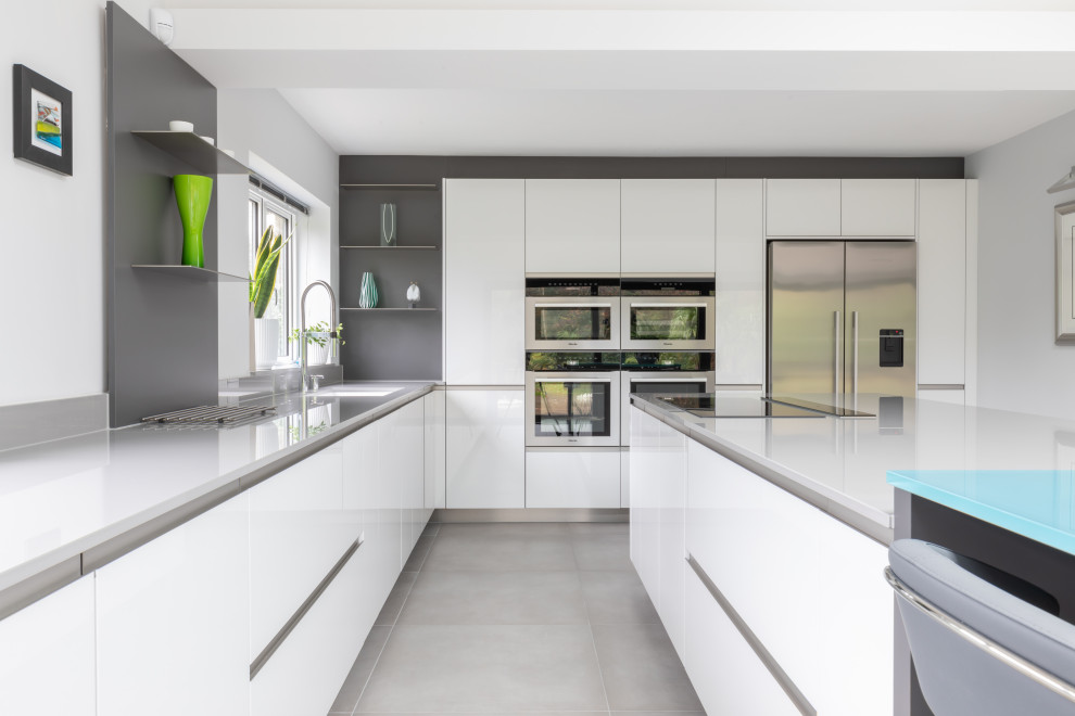 Foto di una grande cucina minimal con ante lisce, ante bianche, top in superficie solida, paraspruzzi grigio e top grigio