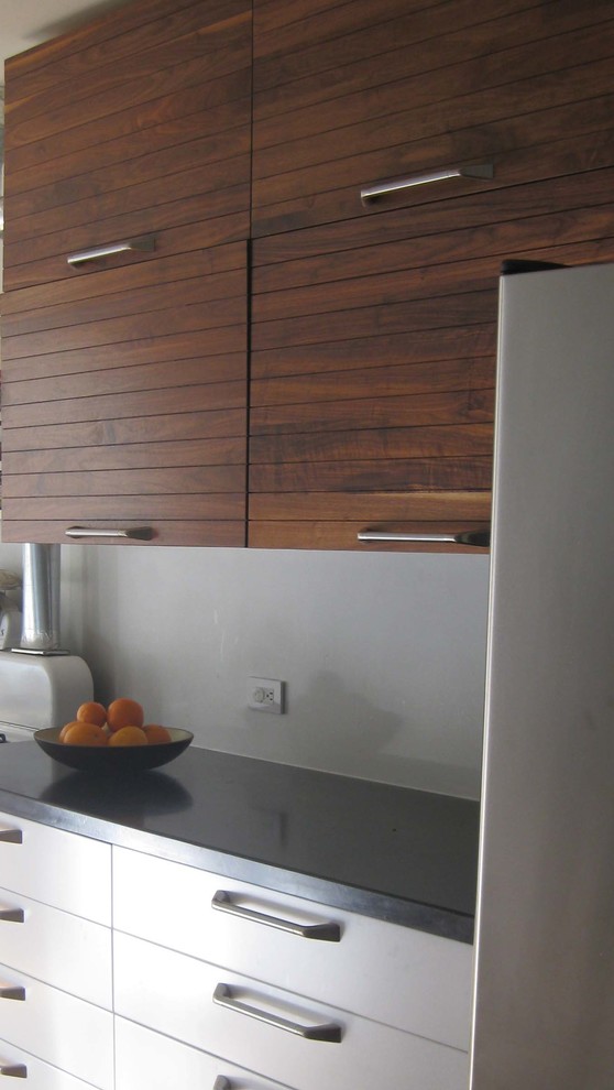 This is an example of a mid-sized modern l-shaped eat-in kitchen in San Francisco with an undermount sink, flat-panel cabinets, medium wood cabinets, granite benchtops, grey splashback, stainless steel appliances, light hardwood floors and a peninsula.