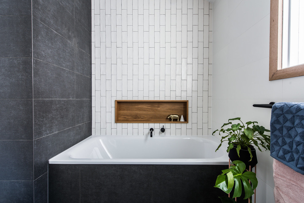 This is an example of a contemporary kids bathroom in Melbourne with furniture-like cabinets, medium wood cabinets, a drop-in tub, a one-piece toilet, black and white tile, porcelain tile, porcelain floors, a vessel sink, engineered quartz benchtops and black floor.
