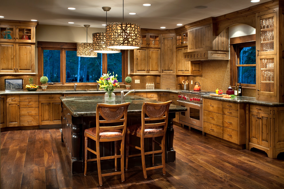 Mountain style u-shaped dark wood floor kitchen photo with a double-bowl sink, raised-panel cabinets, medium tone wood cabinets, granite countertops, brown backsplash, mosaic tile backsplash, stainless steel appliances and an island