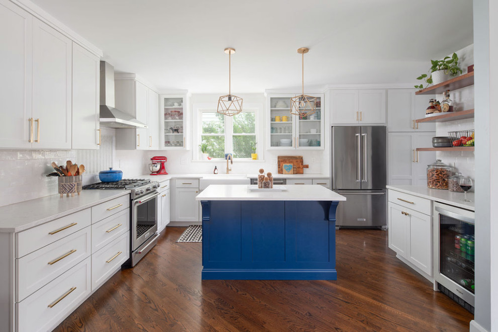 Large transitional u-shaped medium tone wood floor and brown floor eat-in kitchen photo in Columbus with a farmhouse sink, shaker cabinets, white cabinets, quartz countertops, white backsplash, ceramic backsplash, stainless steel appliances, an island and white countertops