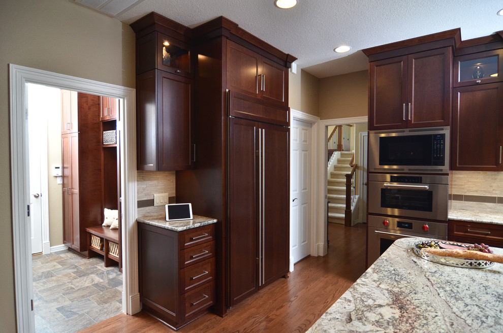 Example of a mid-sized transitional medium tone wood floor eat-in kitchen design in Portland with an undermount sink, recessed-panel cabinets, medium tone wood cabinets, granite countertops, beige backsplash, porcelain backsplash, stainless steel appliances and an island