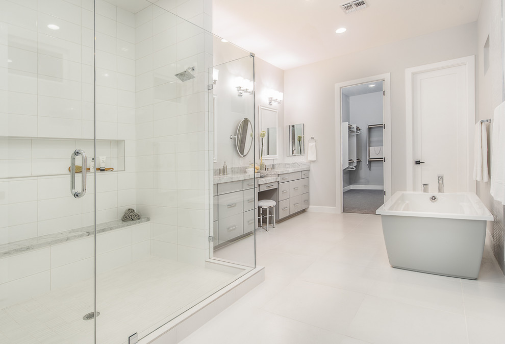Photo of a transitional master bathroom in Phoenix with a pedestal sink, flat-panel cabinets, grey cabinets, marble benchtops, a freestanding tub, an open shower, a one-piece toilet, white tile, grey walls, porcelain floors and a hinged shower door.