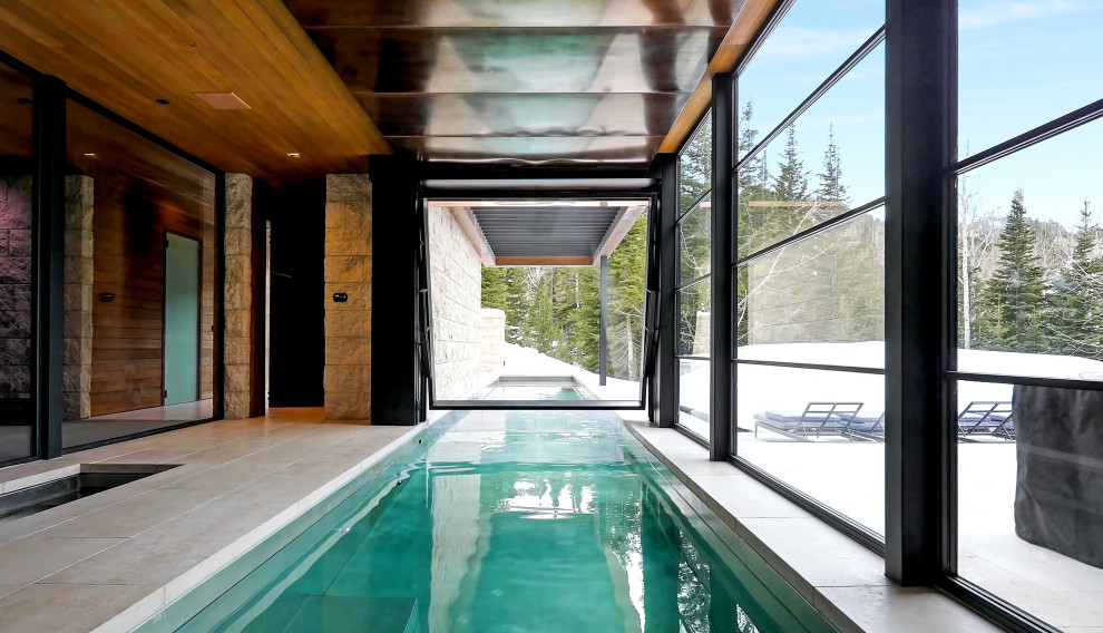 This is an example of an expansive modern indoor rectangular lengths swimming pool in Salt Lake City with natural stone paving.