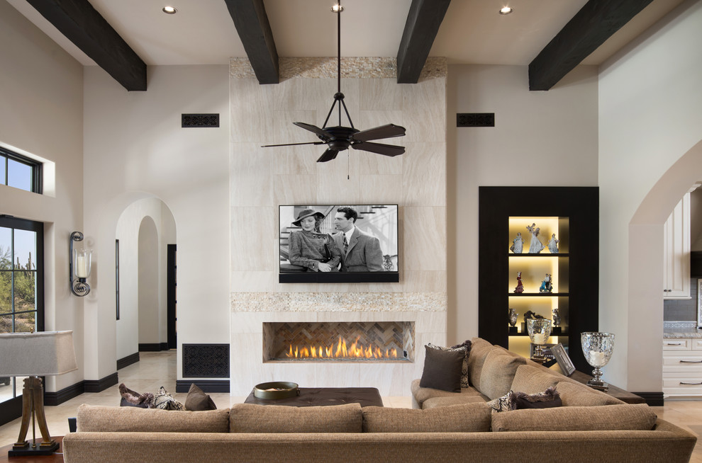 Mediterranean living room in Phoenix with white walls, a ribbon fireplace, a tile fireplace surround, a wall-mounted tv and beige floor.