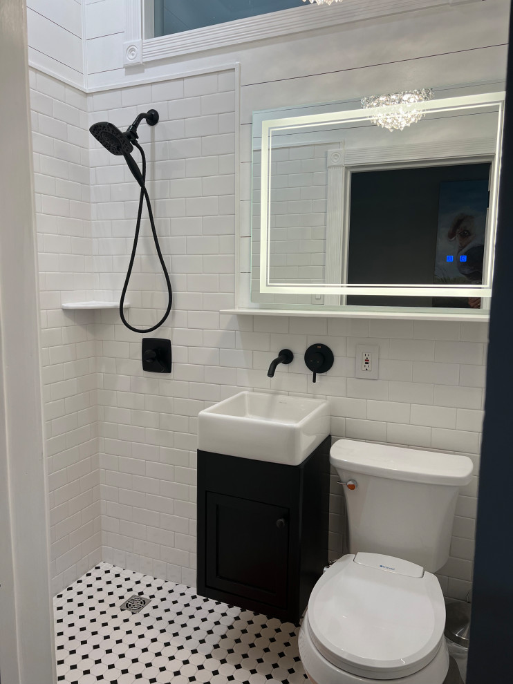 Small country 3/4 bathroom in San Luis Obispo with recessed-panel cabinets, black cabinets, a curbless shower, a two-piece toilet, white tile, ceramic tile, white walls, ceramic floors, a vessel sink, white floor, a sliding shower screen, a single vanity, a floating vanity and planked wall panelling.