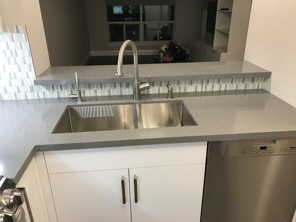 Small contemporary u-shaped eat-in kitchen in Toronto with an undermount sink, flat-panel cabinets, white cabinets, wood benchtops, multi-coloured splashback, porcelain splashback, stainless steel appliances, laminate floors, with island, grey floor and grey benchtop.