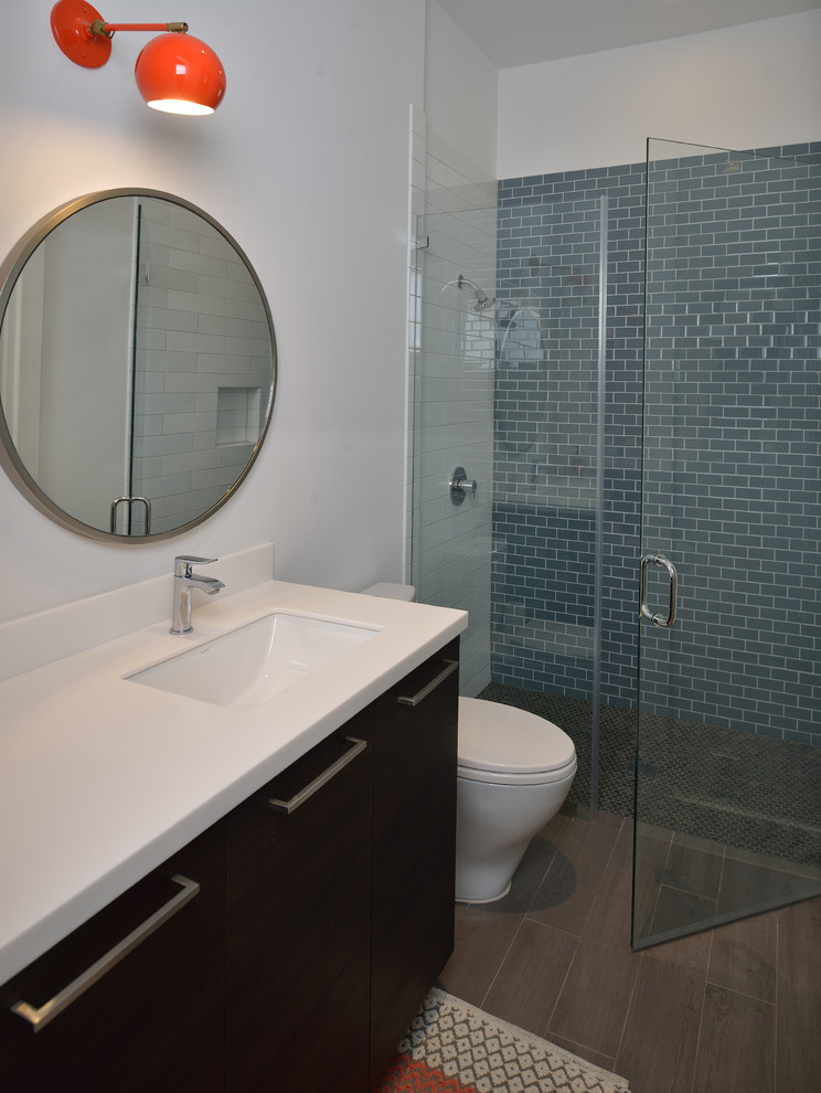 Design ideas for a mid-sized bathroom in Houston with flat-panel cabinets, brown cabinets, a one-piece toilet, blue tile, ceramic tile, white walls, porcelain floors, an undermount sink, stainless steel benchtops and brown floor.