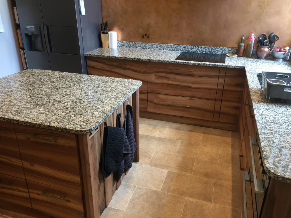 Example of a mid-sized 1950s l-shaped vinyl floor and beige floor kitchen design in Other with an undermount sink, flat-panel cabinets, dark wood cabinets, granite countertops, metallic backsplash, metal backsplash, paneled appliances, an island and gray countertops