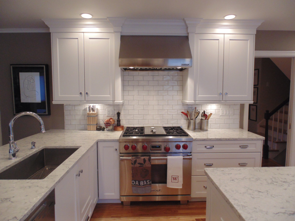 Eat-in kitchen - large transitional u-shaped medium tone wood floor and brown floor eat-in kitchen idea with an undermount sink, recessed-panel cabinets, white cabinets, quartz countertops, white backsplash, subway tile backsplash, stainless steel appliances, an island and white countertops