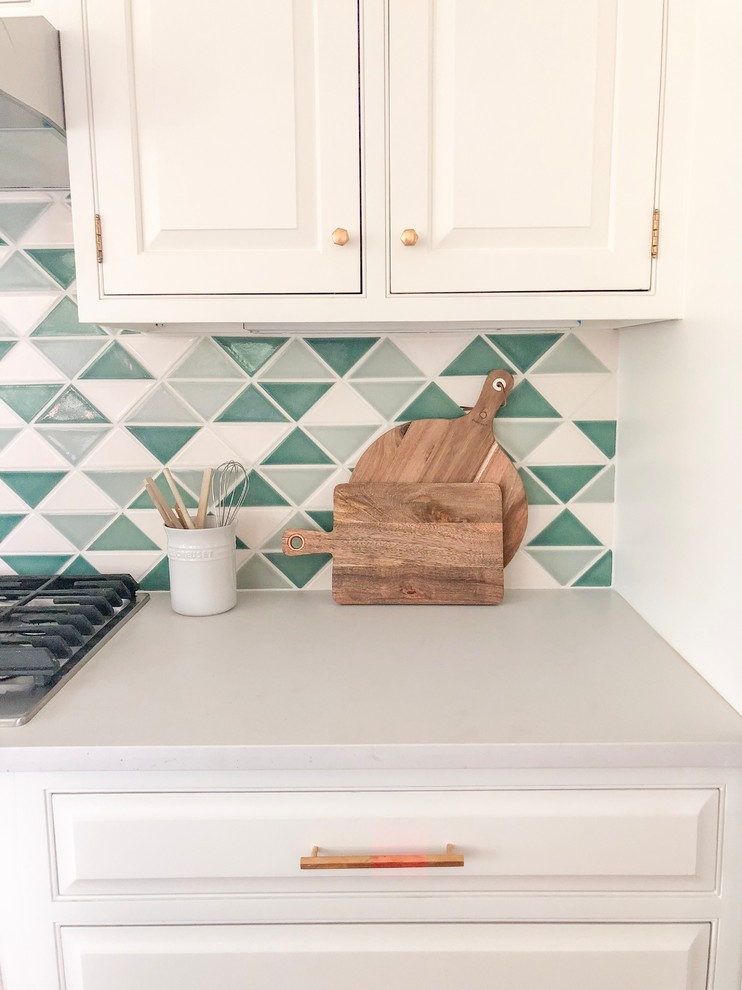 Eat-in kitchen - eat-in kitchen idea in Chicago with raised-panel cabinets, white cabinets, quartz countertops, green backsplash, an island and white countertops