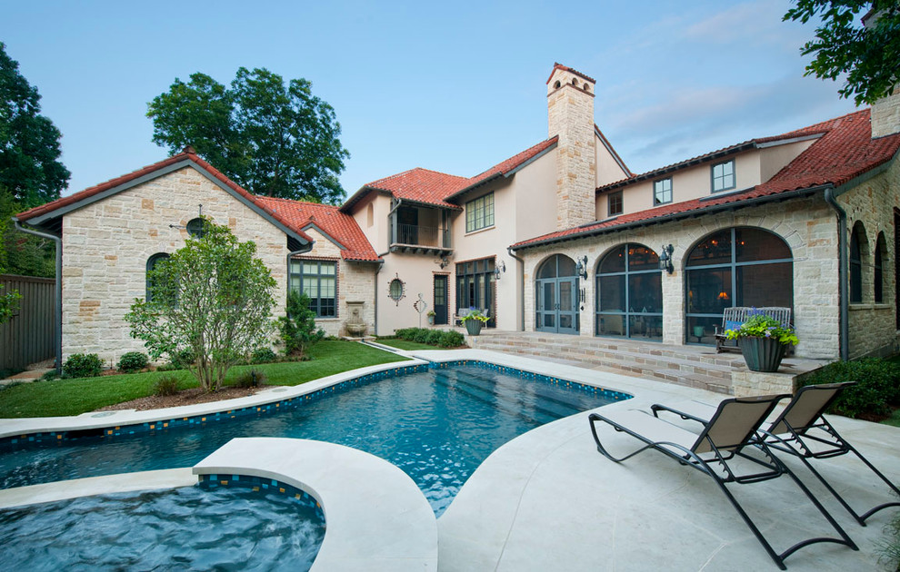 Inspiration for a large mediterranean two-storey beige exterior in Dallas with stone veneer and a tile roof.
