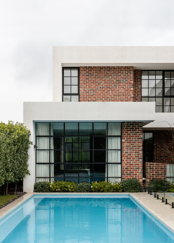 Großer Moderner Pool hinter dem Haus in rechteckiger Form mit Pool-Gartenbau und Natursteinplatten in Melbourne