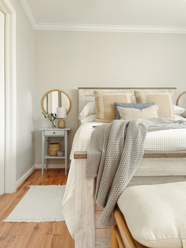 Foto på ett litet minimalistiskt gästrum, med grå väggar, laminatgolv och brunt golv