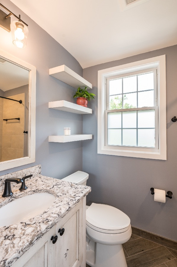 Inspiration for a small country 3/4 bathroom in DC Metro with shaker cabinets, distressed cabinets, a shower/bathtub combo, a two-piece toilet, grey walls, ceramic floors, an undermount sink, granite benchtops, brown floor, multi-coloured benchtops, a single vanity and a built-in vanity.