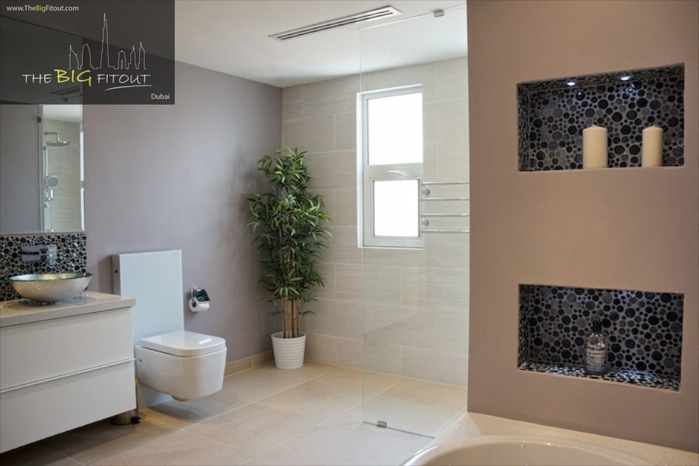 This is an example of a modern master bathroom in Other with a vessel sink, flat-panel cabinets, white cabinets, a drop-in tub, an open shower, a one-piece toilet, beige tile, ceramic tile and ceramic floors.