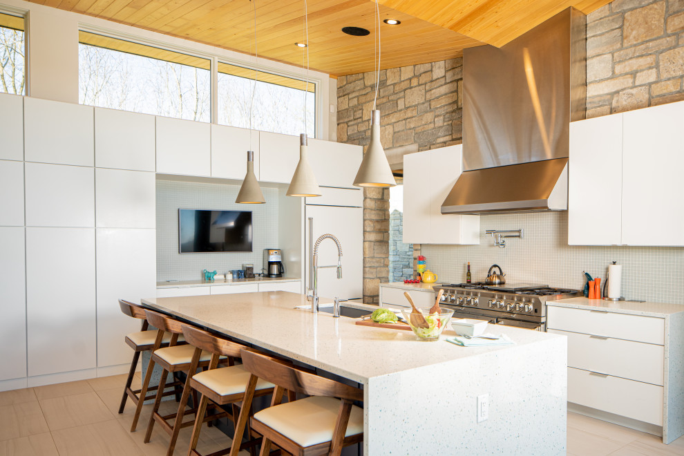 Design ideas for a mid-sized contemporary l-shaped open plan kitchen in Cincinnati with a single-bowl sink, flat-panel cabinets, white cabinets, quartz benchtops, blue splashback, ceramic splashback, stainless steel appliances, ceramic floors, with island, beige floor and white benchtop.
