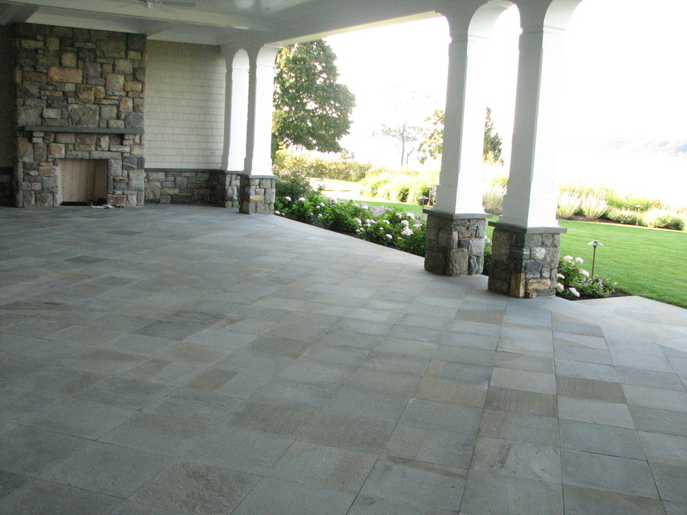 Design ideas for a mid-sized traditional backyard patio in New York with natural stone pavers and a roof extension.