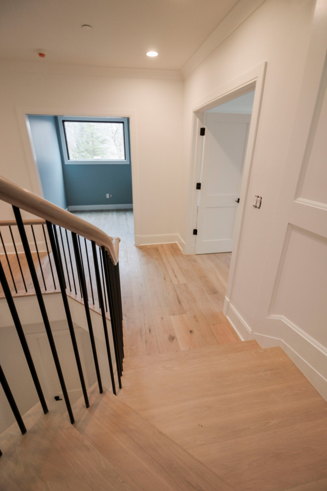 Photo of a large classic wood floating mixed railing staircase in DC Metro with painted wood risers and wainscoting.