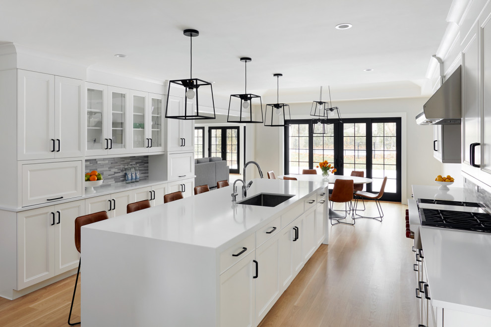 Mid-sized contemporary u-shaped eat-in kitchen in New York with an undermount sink, shaker cabinets, white cabinets, stainless steel appliances, medium hardwood floors and with island.