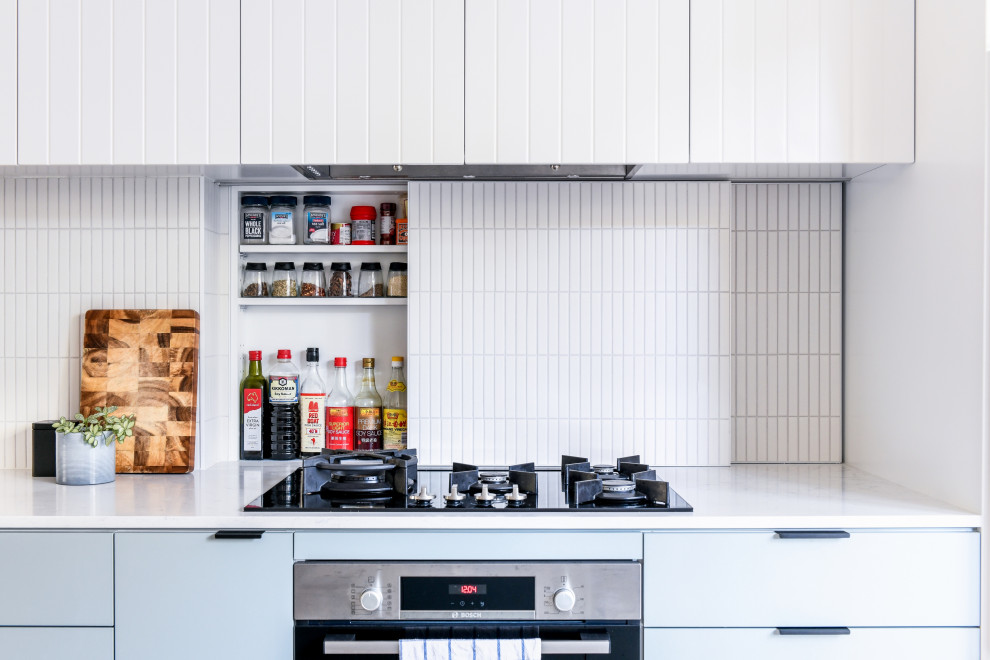 Esempio di una cucina moderna di medie dimensioni con lavello sottopiano, ante lisce, ante blu, top in quarzo composito, paraspruzzi bianco, paraspruzzi con piastrelle a mosaico, elettrodomestici in acciaio inossidabile, pavimento in laminato, pavimento marrone e top bianco