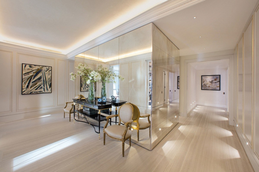 Example of a large classic light wood floor, beige floor, wainscoting and tray ceiling hallway design in London with white walls