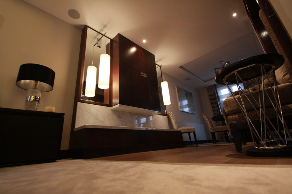 Mid-sized contemporary open concept living room in Essex with a library, beige walls, dark hardwood floors, a standard fireplace, a stone fireplace surround and a wall-mounted tv.