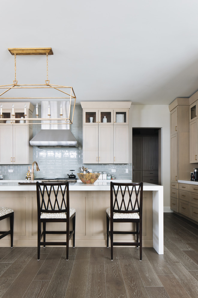Inspiration for a large transitional u-shaped kitchen in Chicago with an undermount sink, shaker cabinets, beige cabinets, quartz benchtops, glass tile splashback, stainless steel appliances, medium hardwood floors, with island, brown floor and white benchtop.