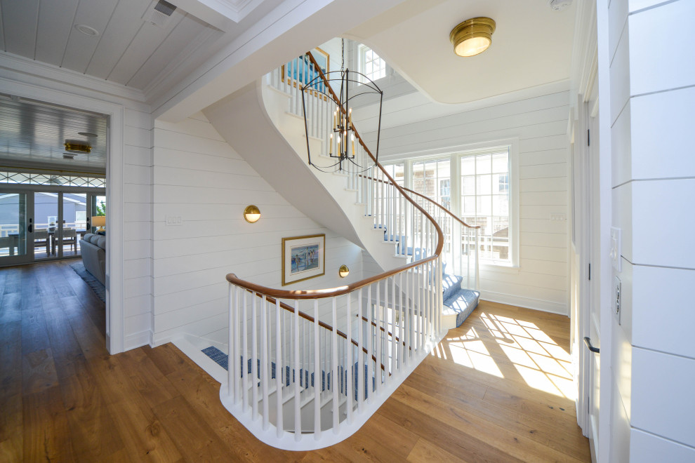 This is an example of a large nautical painted wood curved wood railing staircase in Philadelphia with painted wood risers and tongue and groove walls.